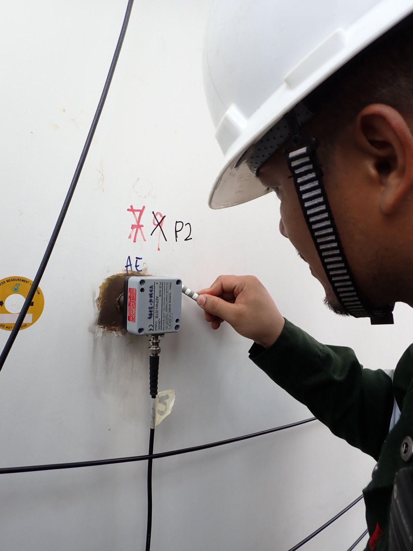 Technician fitting a Vallen AE sensor to a tank shell